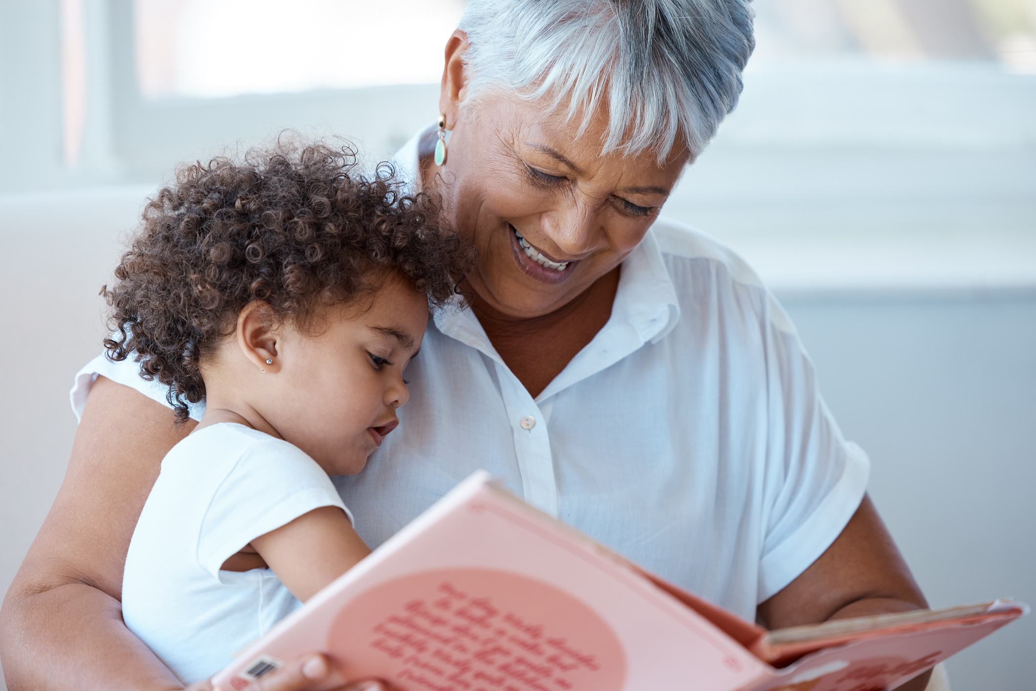 Grandmother reading a book with her young grandchild on the sofa