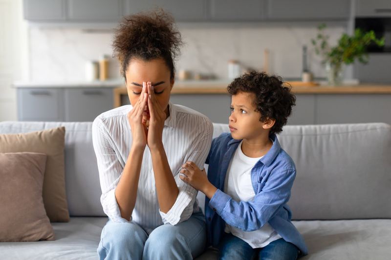 Worried parent with child offering comfort on a sofa