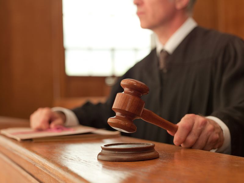 Judge holding a gavel at the bench in a courtroom