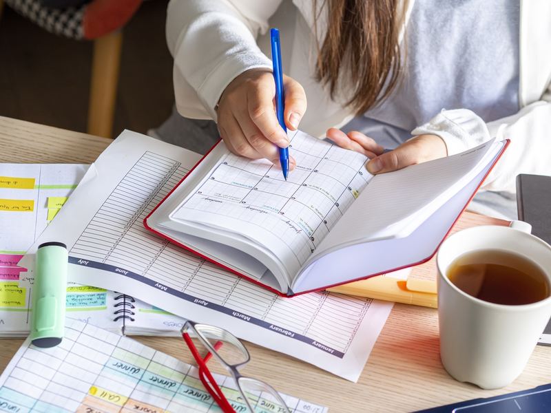 Person writing in a calendar planner at a desk