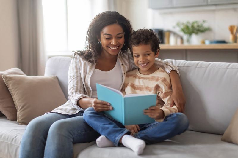 Mother and son reading a book together on the sofa